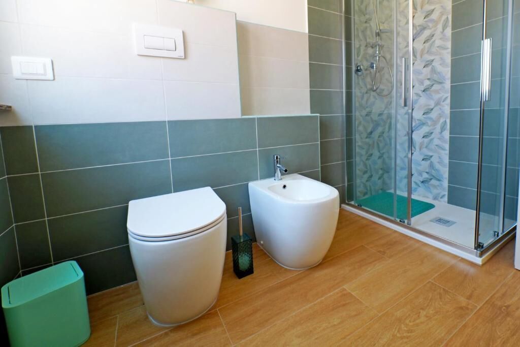 A bathroom with a toilet, bidet, and glass-enclosed shower.