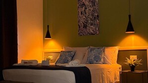 A hotel room with a bed, bedside tables, a wall-mounted artwork, and pendant lighting. - Casa Teresa Guest Rooms (Parghelia)