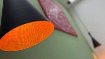 A close-up of a black and orange cone-shaped object, possibly a decorative item, against a green wall with a red patterned object in the background.