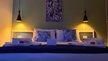 A hotel room with a bed, two bedside lamps, a wall art piece, and a sign on the bed.