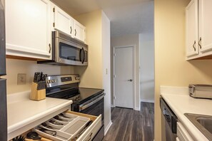 A compact kitchen with white cabinets, a microwave, stove, and a dishwasher. - Keystone Garden Villa E (Indianapolis)