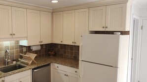 A kitchen with beige cabinets, a granite countertop, a stainless steel sink, and a white refrigerator. - Lovely 2-bedroom condo in Bromley Village perfect for a relaxing getaway (Peru)