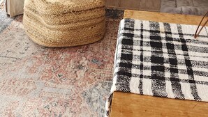 A cozy living room with a fireplace, a white armchair, a round ottoman, and a patterned rug. - Lovely 2-bedroom condo in Bromley Village perfect for a relaxing getaway (Peru)