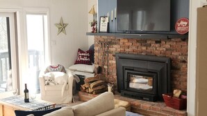 A living room with a sofa, a fireplace, a television, and a dog. - Lovely 2-bedroom condo in Bromley Village perfect for a relaxing getaway (Peru)