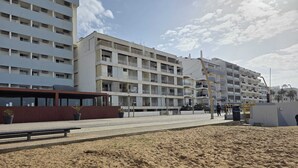 Um hotel à beira-mar com vários andares, varandas e uma área de praia arenosa.