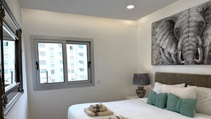 Um quarto com uma cama grande, uma janela, um quadro e uma mesa de cabeceira.