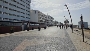 Um hotel à beira-mar com vários andares, um caminho pavimentado e céu claro.