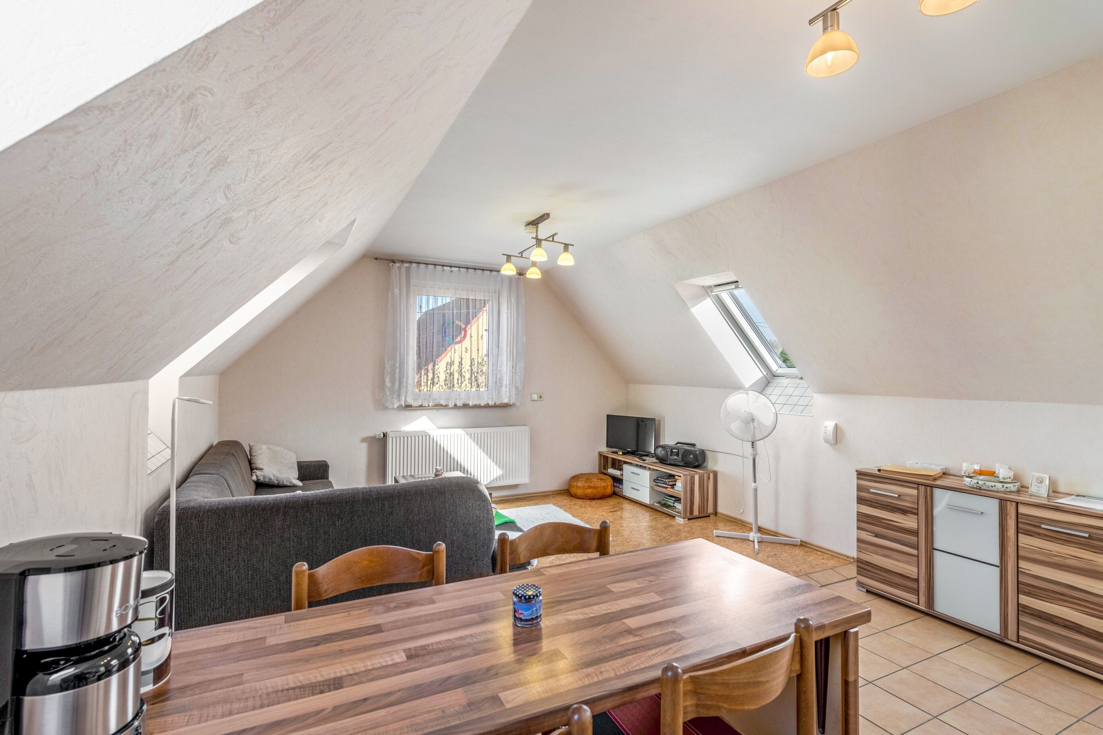 Ein stilvolles Loftzimmer mit Essbereich, Küchenzeile und großem Fenster.