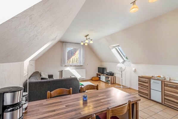 Un moderno espacio tipo loft con zona de comedor, kitchenette y un ventanal grande.