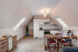 Una cocina compacta con comedor, que incluye estufa, microondas y refrigerador pequeño.