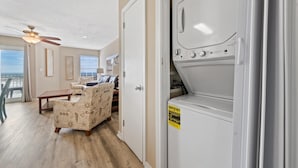 A laundry room with a front-loading washer and dryer, a ceiling fan, and a view to the outside. - Grand Beach Resort 310 (Gulf Shores)