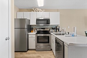A modern kitchen with stainless steel appliances, white cabinets, and a tiled backsplash. - Grand Beach Resort 310 (Gulf Shores)