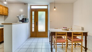 A kitchen with wooden cabinets, a dining table with chairs, a fan, and a light fixture.