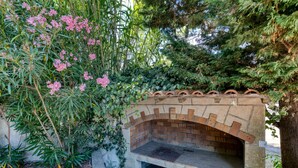 A brick-built outdoor fireplace surrounded by lush greenery and flowering plants.