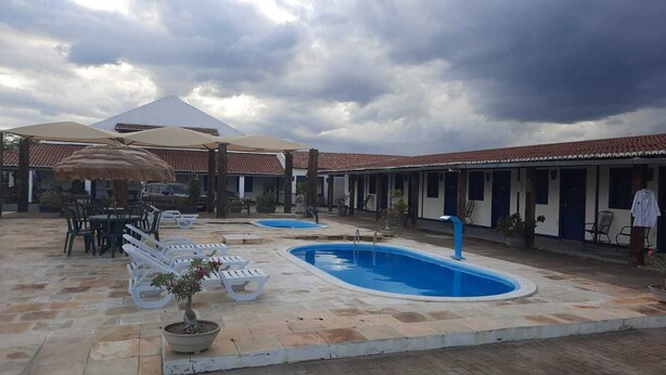 A courtyard with a swimming pool, lounge chairs, and a covered seating area. - Hotel fazenda serrota t (Currais Novos)