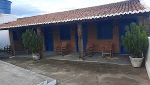 A building with a tiled roof, blue doors, and potted plants. - Hotel fazenda serrota t (Currais Novos)