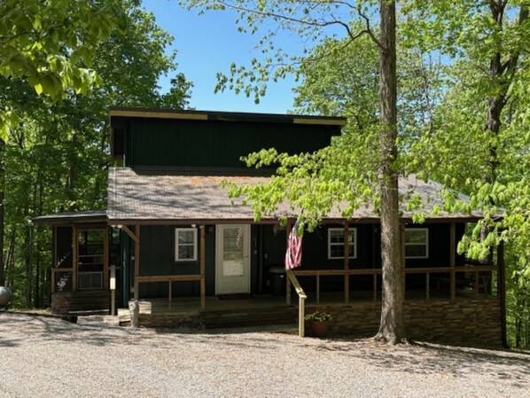 Eine rustikale Holzhütte mit Veranda, einer Tür und einer amerikanischen Flagge.