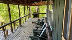 Une terrasse extérieure couverte, dotée de bancs en bois et d’un barbecue.