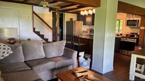 Un salon avec un canapé, une table basse en bois et un escalier menant à une cuisine.