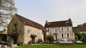 A stone building with a thatched roof, a small garden, and outdoor seating. - Old Presbytery on the waterfront - pets welcome! (Nanteau-sur-Lunain)