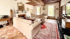 A living room with a fireplace, a sofa, a coffee table, and a large mirror. - Old Presbytery on the waterfront - pets welcome! (Nanteau-sur-Lunain)