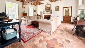 A living room with a sofa, a fireplace, a wooden ceiling, and a stone floor. - Old Presbytery on the waterfront - pets welcome! (Nanteau-sur-Lunain)