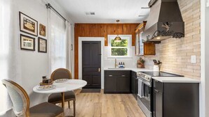 Une cuisine compacte avec un coin repas, comprenant un mur en bois, une cuisinière noire et une fenêtre offrant une vue agréable.