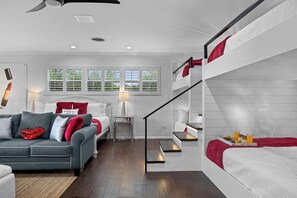 A modern bedroom with a bunk bed, a sofa, a bedside table, and a window with blinds. - Enchanted Vine - Pool, Spa, Sauna & Speakeasy (Fredericksburg)