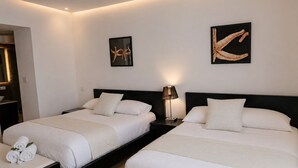 Et hotelværelse med to senge, et natbord med lampe, og billedkunst på væggene.