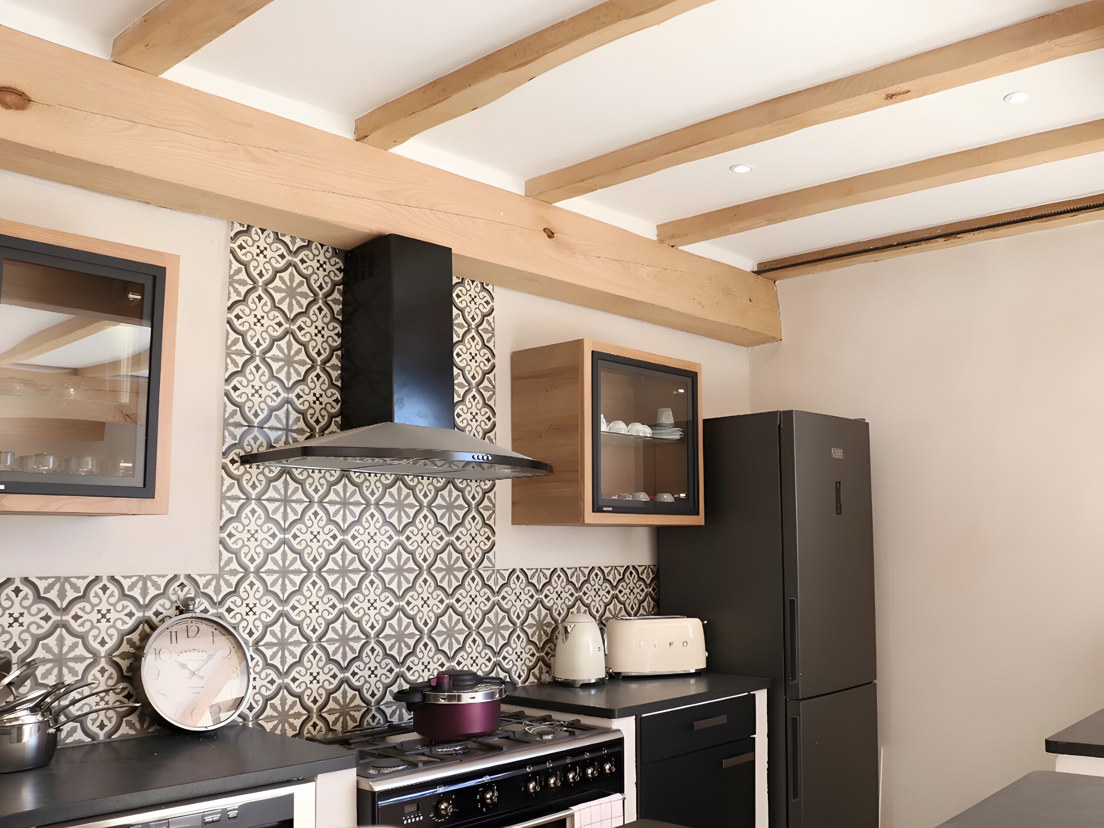 Une cuisine équipée d’une cuisinière, d’un four, d’un réfrigérateur et d’une horloge.