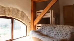 Une pièce dotée d’une structure de plafond en bois, d’une fenêtre et d’un lit recouvert d’une couverture à motifs.