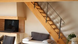 Une pièce de style loft avec un escalier en bois, un canapé, une table à manger et une cheminée.