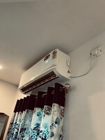 An air conditioning unit mounted on a wall with a power outlet and a warning label.