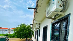 Un edificio con fachada blanca, una puerta verde y un ventanal con reja de metal.