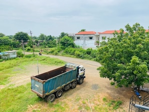 A blue truck parked on a dirt road with a building in the background.