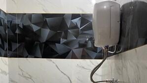 Un baño con inodoro, secamanos y zona de ducha.