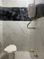A bathroom with a toilet, a hand dryer, and a shower area.