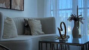 A modern living room with a sofa, decorative pillows, a glass coffee table, and a vase with a plant. - Modern penthouse with Jacuzzi near the airport (Santiago de los Caballeros)