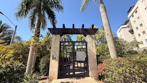 A gated entrance with a pergola, surrounded by palm trees and a building in the background. - Modern penthouse with Jacuzzi near the airport (Santiago de los Caballeros)
