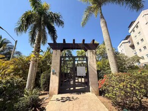 A gated entrance with a pergola, surrounded by palm trees and a building in the background. - Modern penthouse with Jacuzzi near the airport (Santiago de los Caballeros)