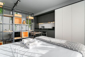 Ein modernes Schlafzimmer mit Bett, integriertem Schreibtisch und einer Küchenzeile.