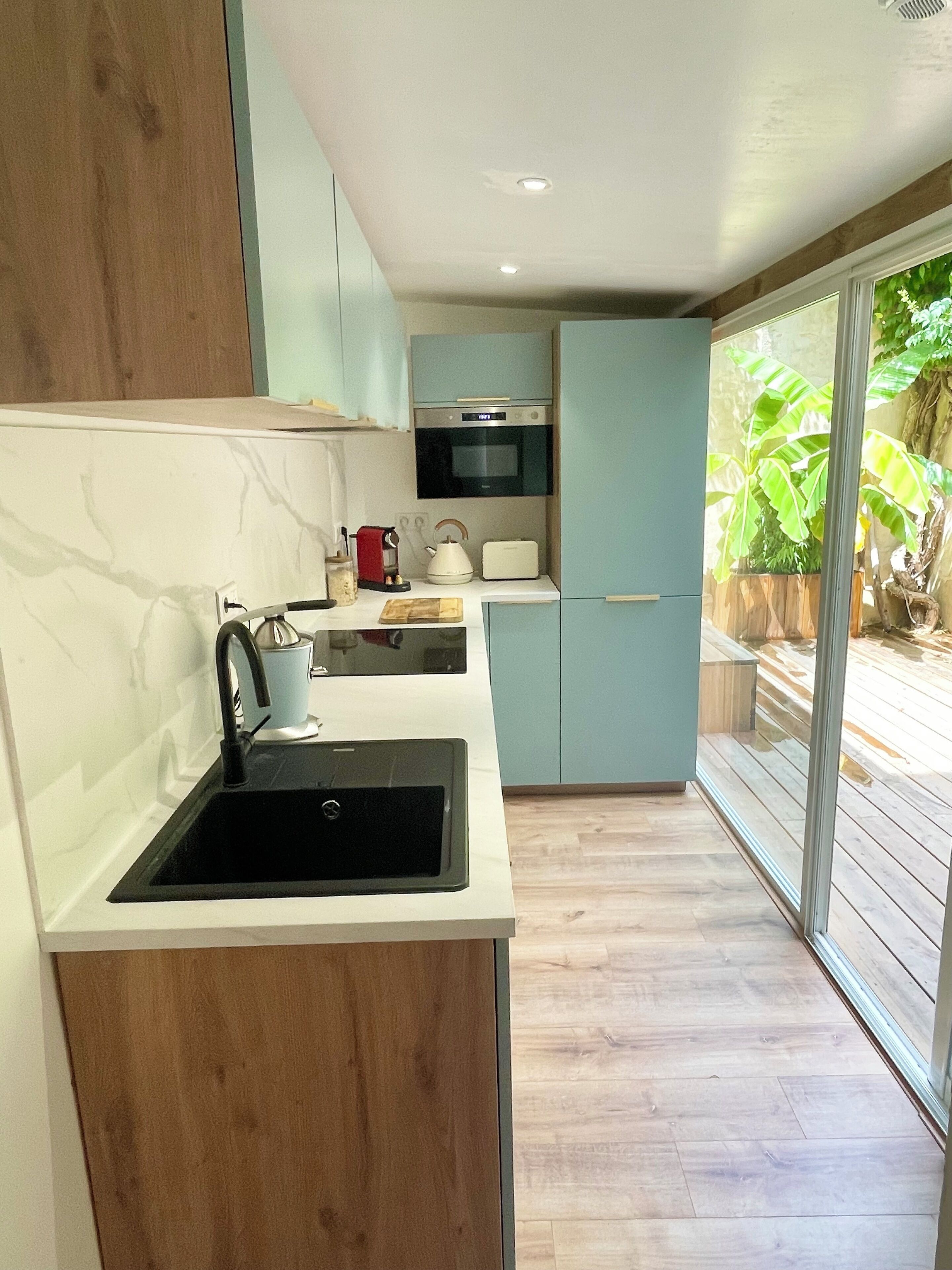 A modern kitchen with a black sink, a kettle, a toaster, and a microwave.