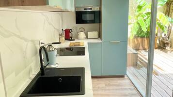 A modern kitchen with a black sink, a kettle, a toaster, and a microwave.