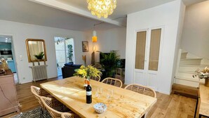 Un coin repas avec une table en bois, des chaises en osier, un vase rempli de fleurs et un luminaire suspendu.