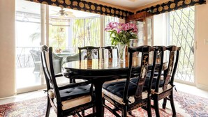 A dining area with a round table, six chairs, and a vase with flowers. - Room-tranquil Poolside Retreat in Playa (Sardinal)