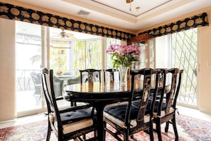 A dining area with a round table, six chairs, and a vase with flowers. - Room-tranquil Poolside Retreat in Playa (Sardinal)