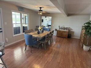 A dining area with a wooden table, blue chairs, and a ceiling fan.