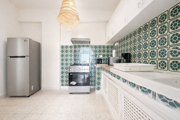 Cozinha com geladeira de aço inoxidável, forno embutido e painel de fundo padronizado.