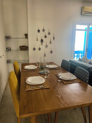A dining area with a wooden table set for four, surrounded by patterned cushions. - Dar Nino Cozy 2 Bedroom Apartment in La Marsa Plage (La Marsa)