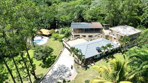 Un complejo turístico con varias edificaciones, piscina y abundante vegetación.